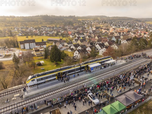 Train stops at a platform in a small town surrounded by people and houses, opening of the Hermann