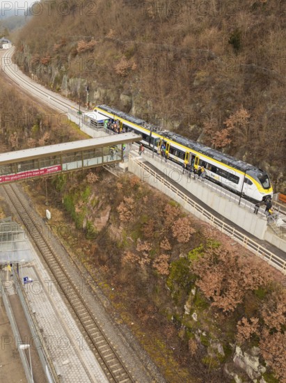 A train stops at an elevated station in a hilly autumn landscape, opening of the Hermann Hesse