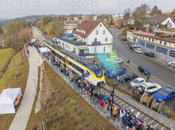 Aerial view of a train on a route with people and rain of confetti next to buildings during an