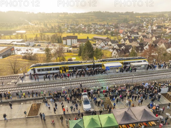 Numerous people at a village train station, festive atmosphere upon arrival by train, opening of
