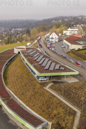 Solar panels on a hill in an urban landscape with cars and houses, opening of the Hermann Hesse