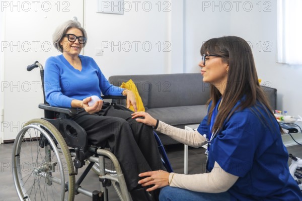 Young female caregiver chatting and smiling with an elderly woman in a wheelchair, offering