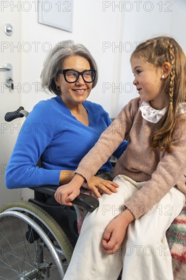 Granddaughter tenderly interacting with her smiling grandmother in a wheelchair, symbolizing strong