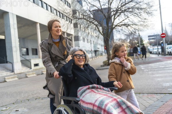 Three generation outing with adult daughter and little girl pushing smiling grandmother in