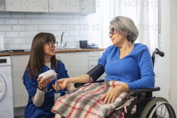 Healthcare professional assisting an elderly woman in a wheelchair by measuring her blood pressure