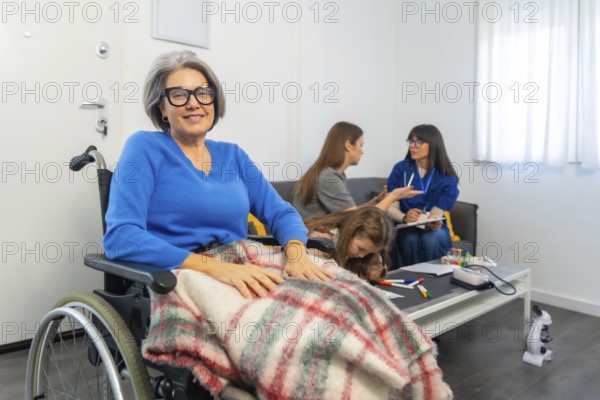 Elder woman in a wheelchair feeling happy while her daughter and granddaughter visit, interacting