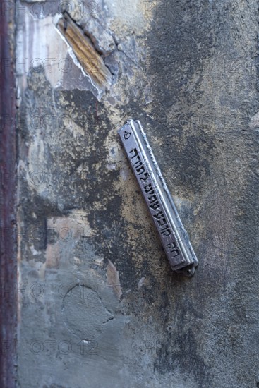 A mezuzah at an entrance to a Jewish house means door post and describes a font capsule on a door