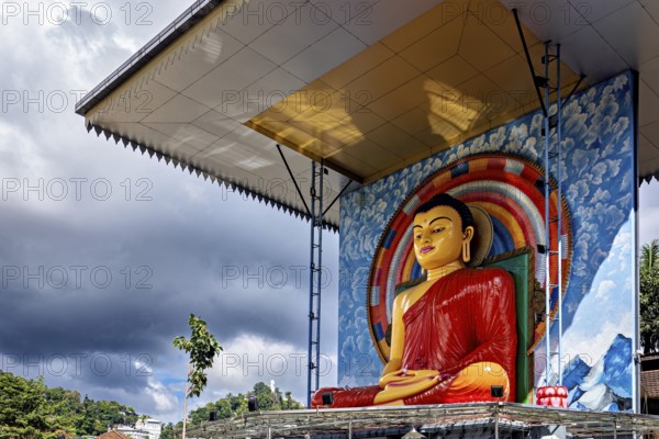 Large Buddha statue under a roof surrounded by rainbow and cloudy sky, Buddha statue in Kandy in