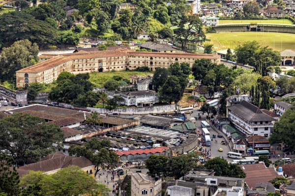View of a historic fortress next to a lawn surrounded by city and trees, view of the city center of