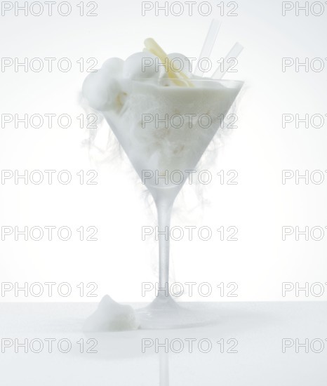 Lemon ice cream in a frosted cocktail glass, the cold creates ice fog on the glass, studio shot