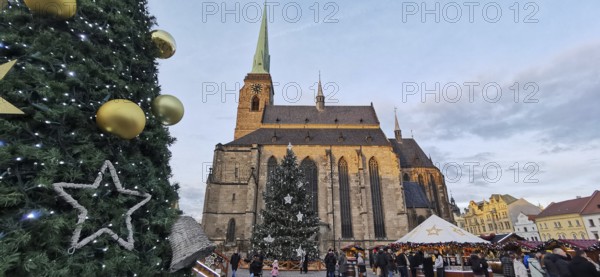 Christmas market in front of a big church with festive decoration and people, Pilsen, Czech
