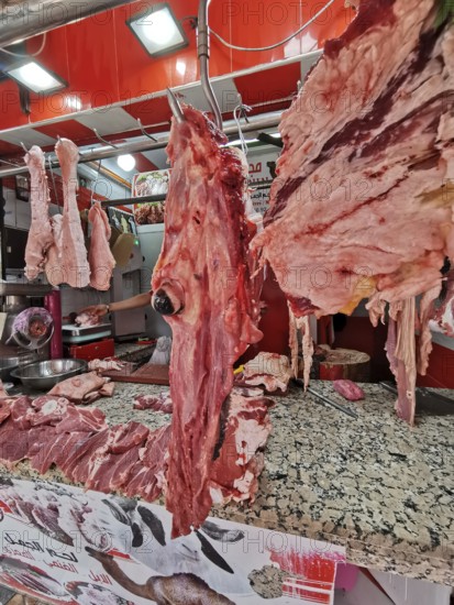 Close-up of pieces of meat and camel's head (camelum) at a lively butcher's stall with red décor,