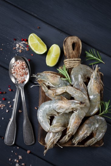 Fresh raw, white-footed shrimp, tiger prawns vannamei, on a wooden cutting board, with lime slices,