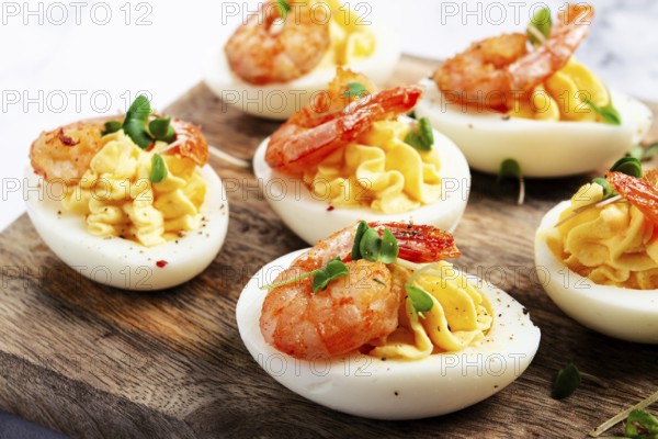Boiled eggs stuffed with yolk and seasoned with mayonnaise, stuffed eggs with shrimp, on a wooden