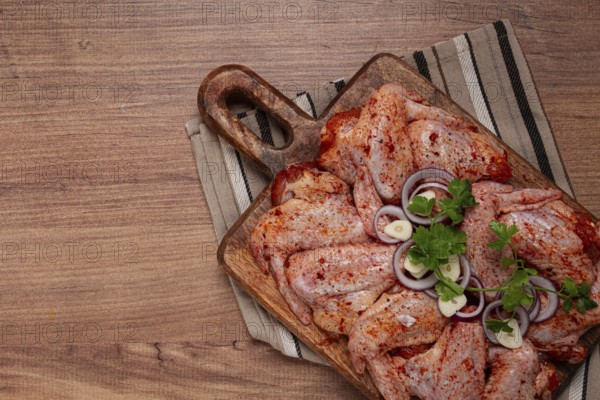 Chicken wings, marinated and laid out on a wooden platter, ready for cooking, grilling or baking,