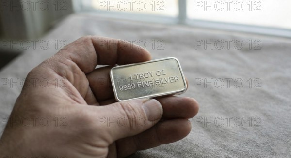Fine silver bar, with neatly stacked silver bullion bars arranged behind it, symbolising precious