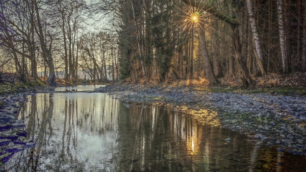 Romantic river landscape at sunset with rays of light through the trees and a peaceful atmosphere,