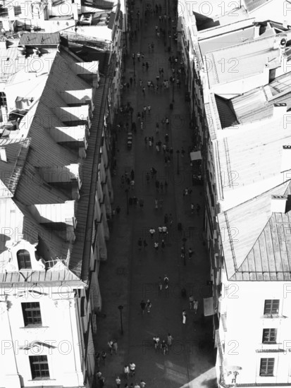 Aerial view of busy street between tall buildings in sunny atmosphere, black and white, Krakow,