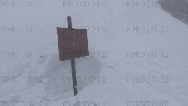 Snowy area with a red sign in thick fog