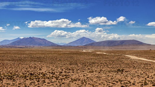 Wide desert landscape with distant mountains and slightly cloudy sky, The landscape of the