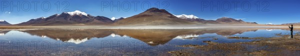 Wide panorama of mountains with reflecting lake and clear sky above the scene, Laguna Colorada in