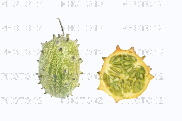 Horned cucumber, kiwano or horned melon (Cucumis metuliferus), whole and sliced fruit on a white