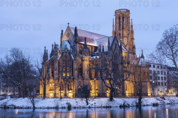 March 18, 2018, winter dusk with snow, illuminated lake and Gothic church Johanneskirche, calm