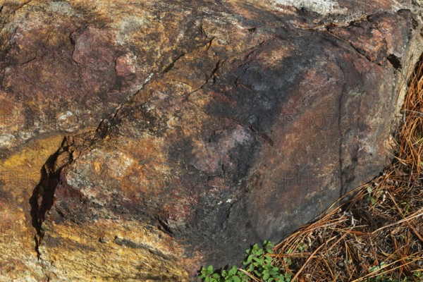 Close-up of outcrop rock surface with nuanced rusted, yellowish, reddish brown and blackened colour