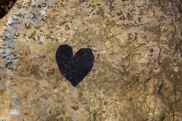 Close-up of painted black heart symbol on tanned nuanced rock surface, Quebec, Canada