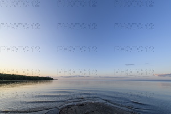 Far-reaching view of the quiet lake Vänern with gently sloping granite rocks archipelago under calm