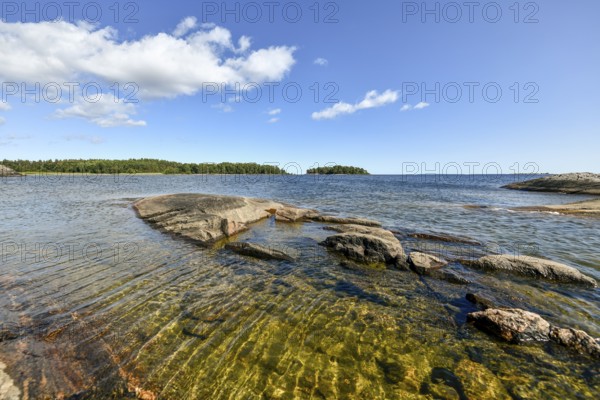 Clear sky over rocky archipelago coastline with granite archipelago with green forest and blue