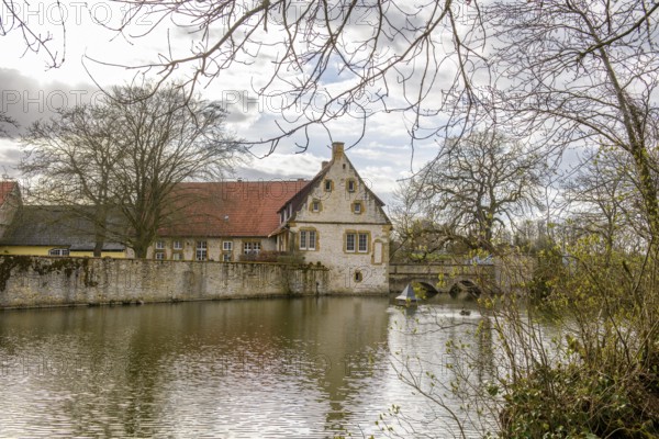An old moated castle in Melle Haus Sondermühlen with bridge, surrounded by a large pond and trees