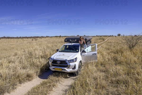 Tourist observes animals through binoculars near the Baines Baobabs, Nxai-Pan National Park, near