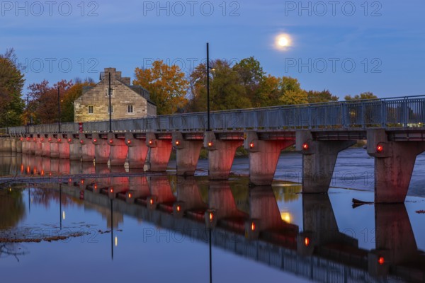 Illuminated Moulin Neuf water flow control dam and walkway over Des Mille-Iles river plus New Mill