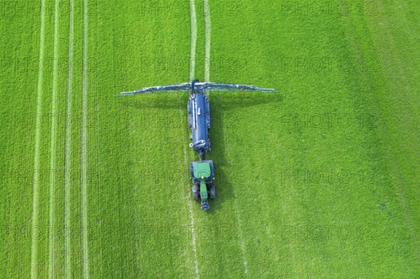 Aerial view over tractor towed liquid manure spreader, slurry spreader enabling the fertilization