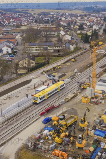 Construction site with crane and yellow train at a municipal train station, surrounded by