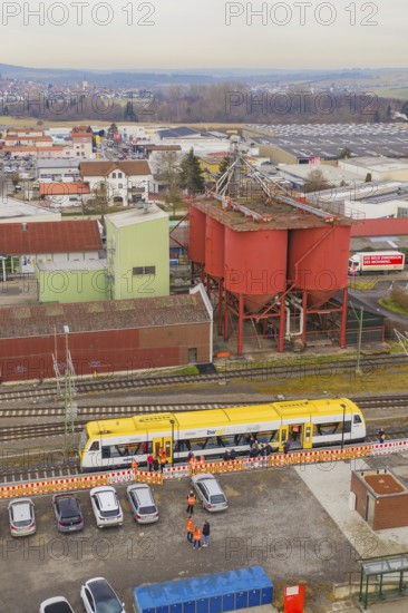 Aerial view of an industrial area with a yellow train and large red buildings, taking the Hermann