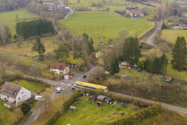 Rural landscape with individual houses, fields and a yellow train on the tracks, acceptance of the