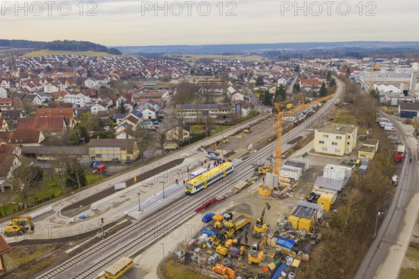 Aerial view of urban construction site with yellow train on tracks and residential buildings,