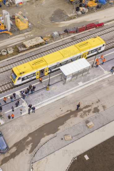 A bird's eye view of a yellow train at a train station with people, taking the Hermann Hesse