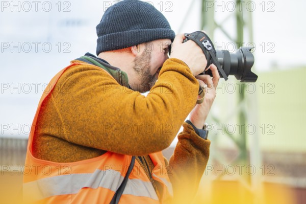 A photographer wears a safety vest and takes pictures at work, taking the Hermann Hesse Railway,