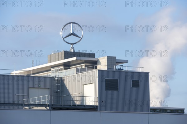 Close-up of a modern building with Mercedes logo and clouds of smoke in the background, blue sky,