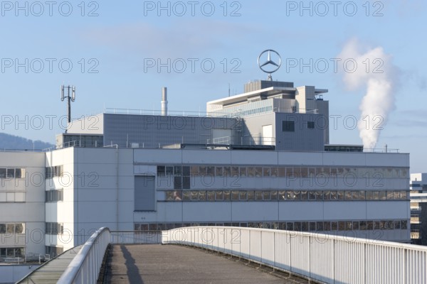 Modern industrial building with Mercedes logo and smoking chimney in the background, blue sky,