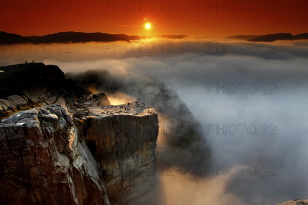 A golden horizon spreads over the sea of clouds and the mighty cliffs of Preikestolen,