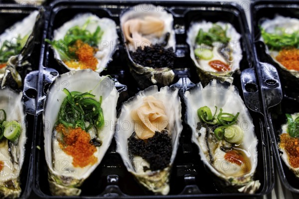 Decoratively presented oysters with green and black toppings at Sydney Fish Market, Sydney, New