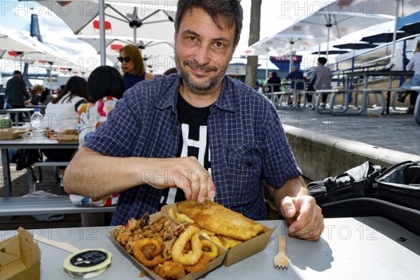 Man enjoying fish and squid rings outdoors at Sydney Fish Market, Sydney, New South Wales,