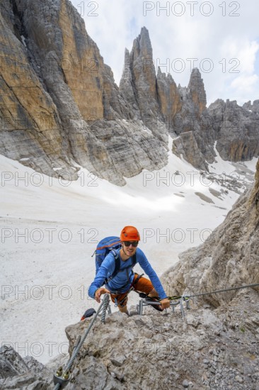 Mountaineer climbs on a steep rock face in the Via Ferrata dell'Ideale via ferrata, spectacular