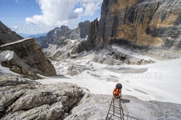 Mountaineer climbs on a ladder in the Via Ferrata Brentari via ferrata, spectacular mountain