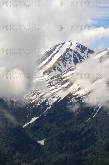 Fog sweeps around mountain peaks with remnants of snow, view from Slaughter Ridge Trail, Cooper