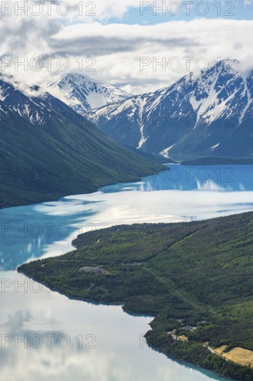 View of snowy mountains in spring and turquoise Kenai Lake with reflection, Slaughter Ridge Trail,